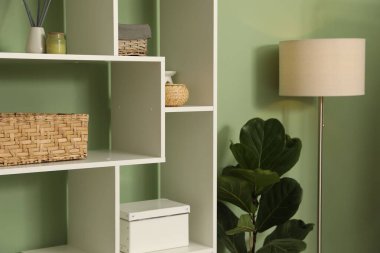 Salon içinde zeytin duvarının yanında farklı dekorasyonu olan ahşap raf ünitesi.