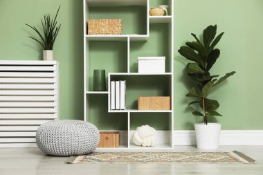 Salon içinde zeytin duvarının yanında farklı dekorasyonu olan ahşap raf ünitesi.