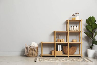 Açık gri duvarın yanında farklı dekorasyona sahip ahşap raf ünitesi.