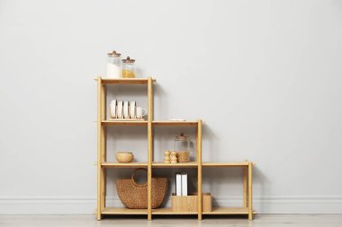 Açık gri duvarın yanında farklı dekorasyona sahip ahşap raf ünitesi.