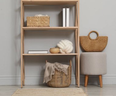 Açık gri duvarın yanında farklı dekorasyona sahip ahşap raf ünitesi.