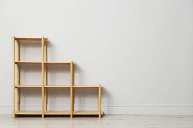 Açık gri duvarın yanındaki boş ahşap raf ünitesi. Metin için boşluk