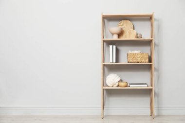 Açık gri duvarın yanında farklı dekorasyona sahip ahşap raf ünitesi. Metin için boşluk
