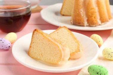 Lezzetli kek parçaları, pembe ahşap masada paskalya yumurtası ve çay, yakın plan.