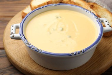 Lezzetli peynir sosu kaseye, kızarmış ekmekler ahşap masaya, yakın plan.