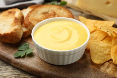 Lezzetli peynir sosu kaseye ve aperatifler masaya, yakın plan.