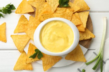 Lezzetli peynir sosu kasede ve nacho cipsi beyaz ahşap masada, düz yerde.