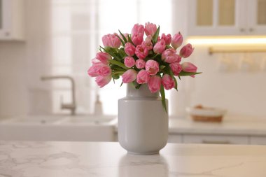 Mutfaktaki beyaz mermer tezgahta vazoda duran bir buket güzel lale.