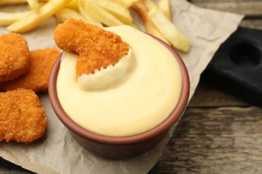 Tabakta nefis peynir sosu, tavuk nugget ve ahşap masada patates kızartması, yakın plan.