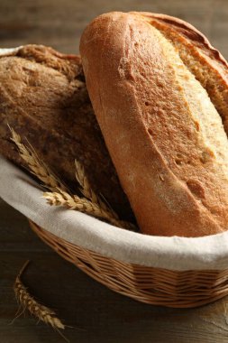 Farklı somunlar taze ekmek ve hasırdan sepetteki çiviler ahşap masada, yakın plan