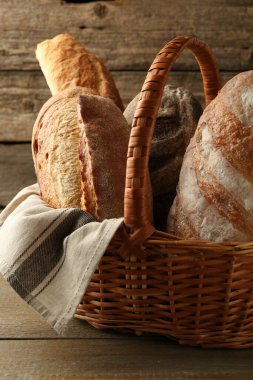 Hasır sepetin içinde farklı somunlar, ahşap masanın üzerinde, yakın plan.