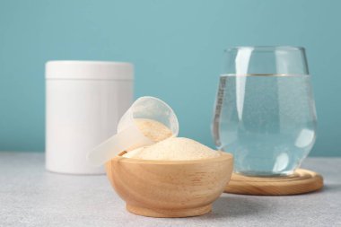 Kolajen tozu ve bir bardak su gri desenli masa üzerinde açık mavi arka plan, yakın plan