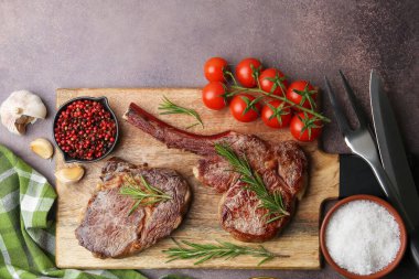 Pieces of delicious beef meat, spices and tomatoes on brown table, top view