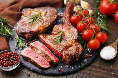 Lezzetli et parçaları, ahşap masada baharatlar ve domatesler, yakın plan.