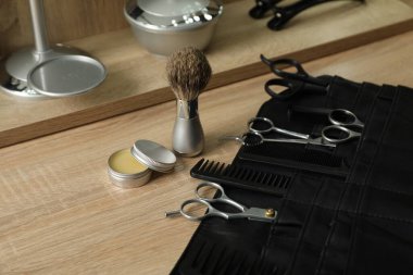 Berber dükkanında, açık ahşap masanın üzerinde birçok farklı berber aleti var.