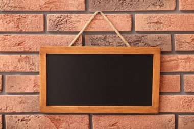 Tuğla duvarda boş küçük bir tahta.
