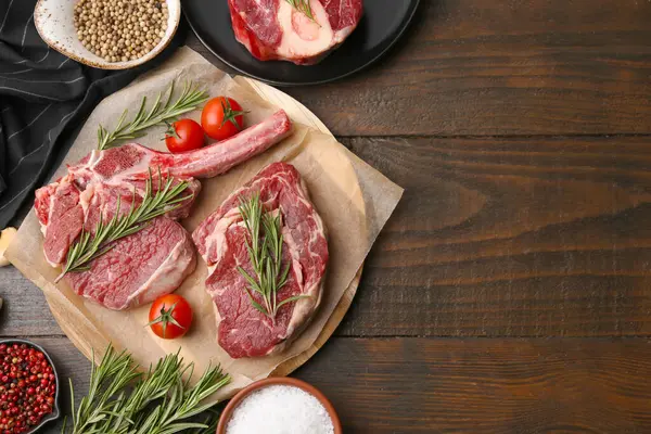 Çiğ et parçaları, domates ve baharatlar ahşap masada, düz yerde. Metin için boşluk