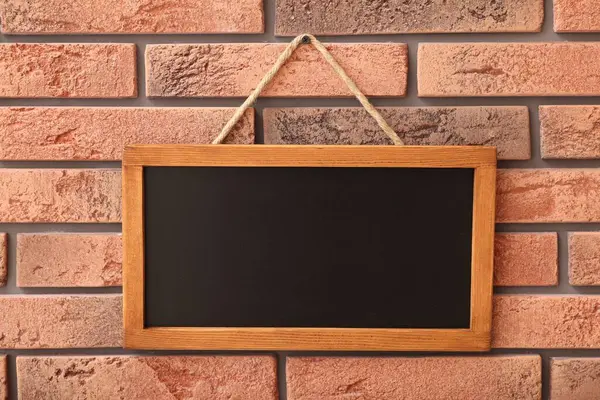 Tuğla duvarda boş küçük bir tahta.