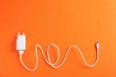 Turuncu arka planda şarj kablosu olan USB güç adaptörü, üst görünüm