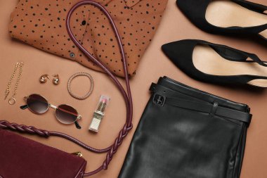 Şık kadın kıyafetleri ve kahverengi arka planda farklı aksesuarlar.