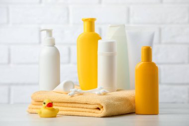 Bebek kozmetik ürünleri, havlu ve plastik ördek beyaz tuğla duvara karşı, yakın plan.