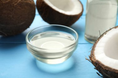 Organik hindistan cevizi pişirme yağı ve açık mavi ahşap masada taze meyveler, yakın plan.