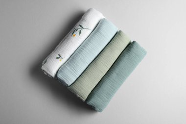 Rolled baby blankets on light grey background, flat lay