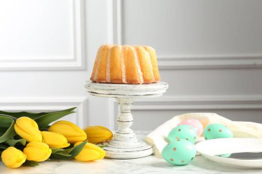 Lezzetli kek, Paskalya yumurtası ve beyaz mermer masada laleler.