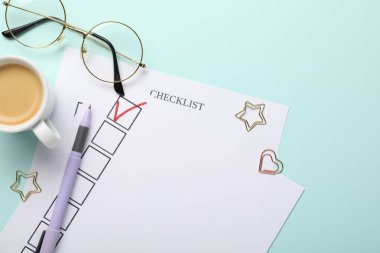 İşaretli onay kutusu, kahve, bardaklar ve ataçlar açık mavi arka planda, düz yatar