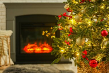 Evdeki şöminenin yanında güzel dekore edilmiş Noel ağacı, yakın çekim. Bokeh etkisi