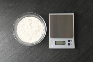 Elektronik mutfak terazisi ve koyu dokulu masa üzerinde un dolu bir kâse.