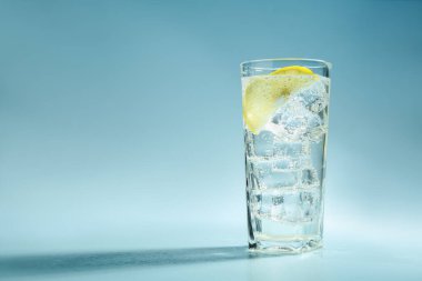 Limonlu soda ve açık mavi zemin üzerinde buzlu cam, metin için alan