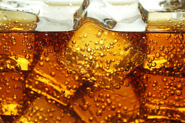 Refreshing soda water with ice cubes as background, closeup