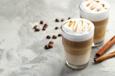 Bardakta latte macchiato, kahve çekirdekleri ve gri masada tarçın, yakın plan. Metin için boşluk