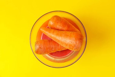 Sarı arka planda taze havuç dolu mutfak terazisi.