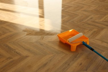Process of polishing. Roller and tray with varnish on floor, space for text