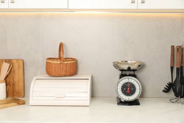 Retro mechanical kitchen scale and other utensils on white marble countertop indoors