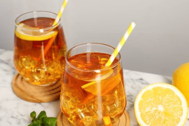 Buzlu çayı limon dilimleriyle, nane şekeriyle ve beyaz mermer masada pipet içerek tazeliyorum.