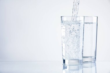 Serinletici gazoz suyunu arka planda bardaklara doldurmak, yakın plan. Metin için boşluk