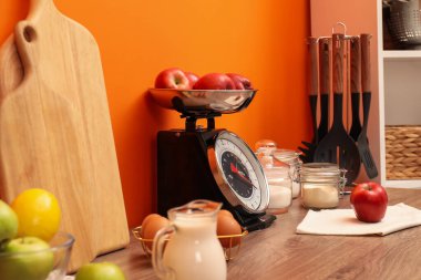 Kitchen scale, products and cooking utensils on wooden table