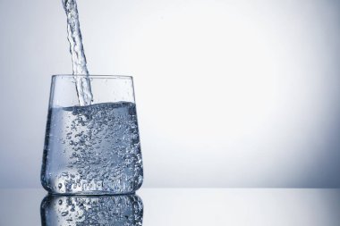 Açık gri arka planda ferahlatıcı soda bardağına dökülüyor, yakın plan. Metin için boşluk