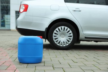 Light blue plastic canister on pavement outdoors