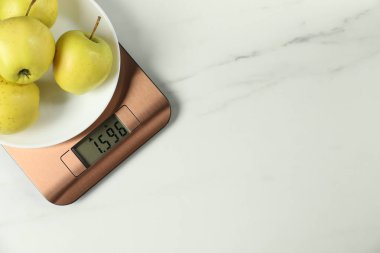 Modern elektronik mutfak terazisi, beyaz mermer masa üzerinde elmalar, üst manzara. Metin için boşluk