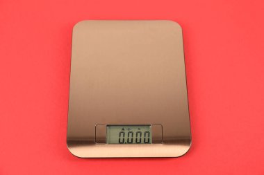 Kırmızı arka planda bir elektronik mutfak terazisi.