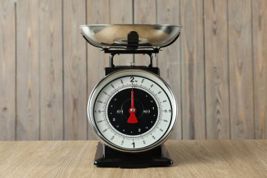 Mechanical kitchen scale with bowl on wooden table