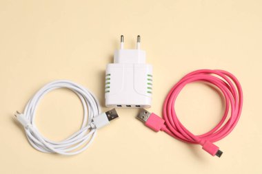Bej arka planda USB güç adaptörü ve şarj kabloları, düz yatıyordu