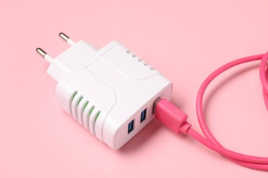 Soluk pembe arkaplanda şarj kablosu olan USB güç adaptörü, yakın plan