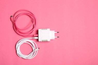 Pembe arka planda şarj kabloları olan USB güç adaptörü, üst görüş. Metin için boşluk