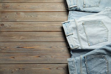 Different stylish jeans on wooden background, flat lay. Space for text