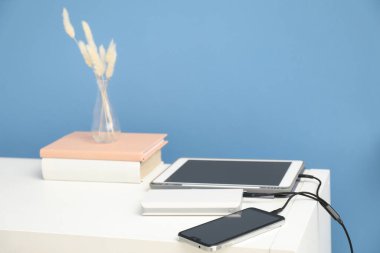 USB şarj kablosu açık mavi duvarın yanındaki raflardaki aygıtlara bağlandı